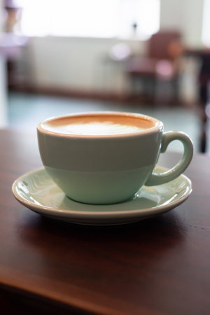 Cup of coffee with latte art on wooden table with soft sunlight.の写真素材