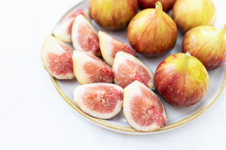 Fresh figs displayed on a plate, highlighting their juicy flesh and vibrant color, perfect for healthy recipes or summer treats.の写真素材