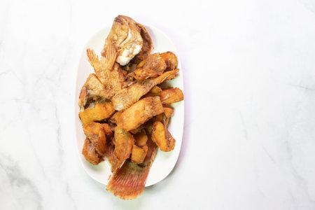 A delicious platter featuring crispy fried fish served with golden brown plantains, perfect for a hearty meal.の写真素材
