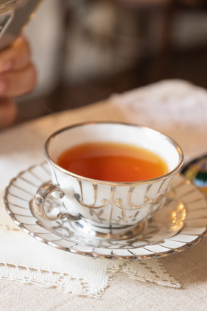 A delicate cup of tea served in a fine china teacup, highlighting the rich amber color and elegant design.の写真素材