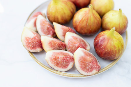 A fresh assortment of figs displayed on a plate, showcasing their vibrant colors and juicy texture, perfect for culinary delights.の写真素材