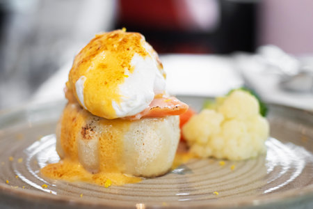 A delicious serving of poached eggs with salmon and a dollop of hollandaise sauce on a bed of creamy cauliflower.の写真素材
