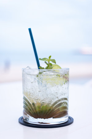 Refreshing cocktail with mint and lime served in a glass, perfect for summer relaxation by the beach.の写真素材