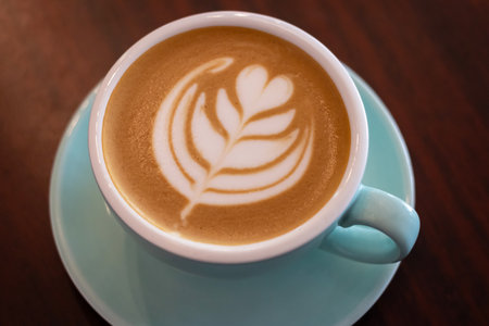 Cup of coffee with latte art on wooden table with soft sunlight.の写真素材