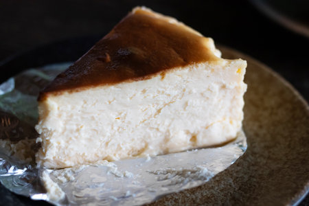 An enticing slice of creamy cheesecake served on a rustic plate, showcasing its rich texture and delightful caramelized top.の写真素材