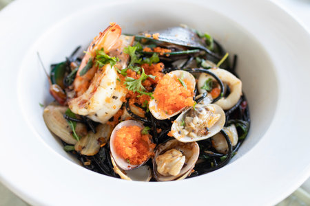 Squid ink spaghetti with garlic, olive oil, chili and seafood on white dish.の写真素材