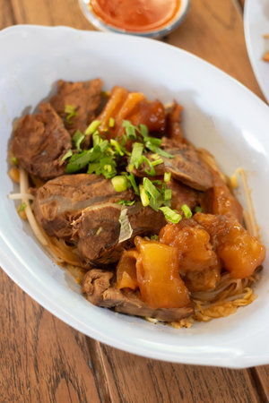 A delicious serving of tender meat with vegetables, garnished with green onions, showcasing vibrant flavors and textures.の写真素材