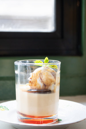 A delectable dessert featuring creamy layers and a topping of rich ice cream, served in an elegant glass on a stylish plate.の写真素材
