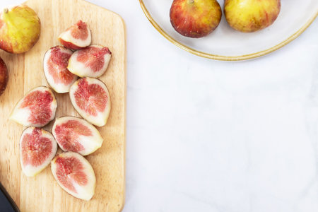 Fresh figs sliced on a wooden board with whole figs in the background, showcasing vibrant colors and textures.の写真素材