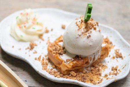 Delicious dessert featuring a scoop of ice cream atop a crunchy base, served with whipped cream and a sprinkle of crumbs.の写真素材