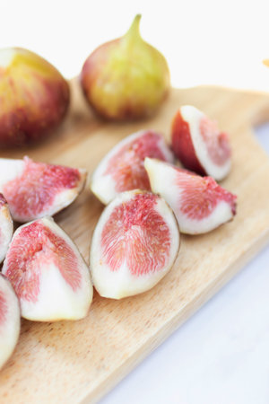 Fresh figs sliced on a wooden board, showcasing their vibrant flesh and unique texture, perfect for culinary inspiration.の写真素材