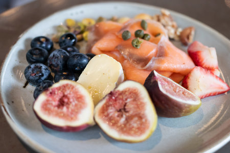 A vibrant plate of fresh fruits including figs, berries, and melon, presenting a colorful and...