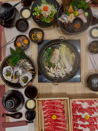 A mixed sashimi hot pot sliced beef oyster salad mushroom tofu broth soy sauce sesameの写真素材