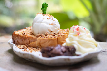 Delicious dessert featuring toasted bread topped with creamy ice cream, whipped cream, and crunchy toppings, perfect for any sweet craving.の写真素材