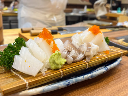 A fresh sashimi platter with squid slices, octopus and roe served with wasabi and parsley on bamboo matの写真素材