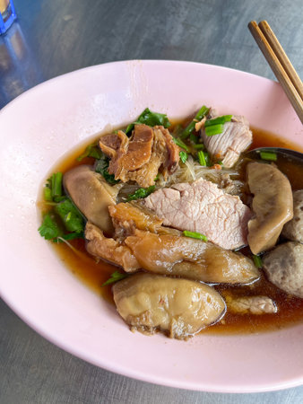 A savory bowl of Asian noodle soup with beef, tender meat garnished with fresh herbs, ready to be enjoyed. Perfect for culinary enthusiasts and food lovers.の写真素材