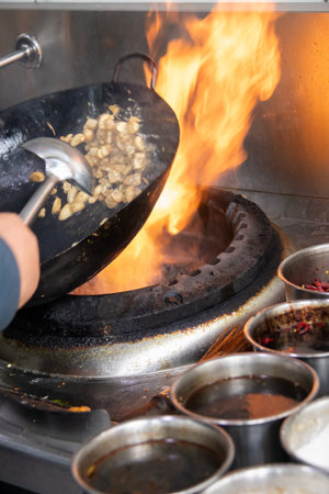 A wok stir fry over high flame with tossing motion, sizzling garlic and vegetables creating...