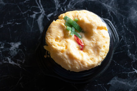 A soft steamed egg custard topped with chopped scallion and chili, warm savory breakfast comfortの写真素材