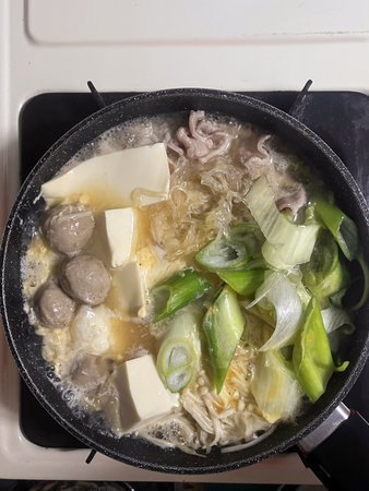 A hot pot soup with tofu meatball noodles and green onion simmering in brothの写真素材