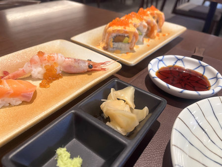 A fresh sushi platter with nigiri, shrimp, salmon rolls and condiments creating warm appetizing sceneの写真素材