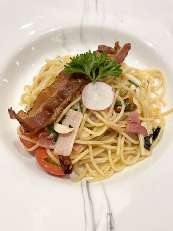 A crisp bacon spaghetti with cherry tomato, garlic and parsley garnish, creamy olive oil pasta delightの写真素材