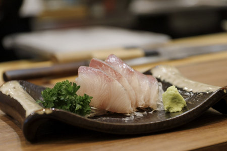 A fresh slices of raw fish sashimi served with wasabi and parsley on ceramic plate, appetizing presentationの写真素材