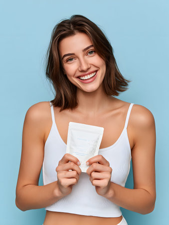 A smiling woman holding pouch of protein powder, skincare or supplement pouch, healthy lifestyle, joyful expressionの素材
