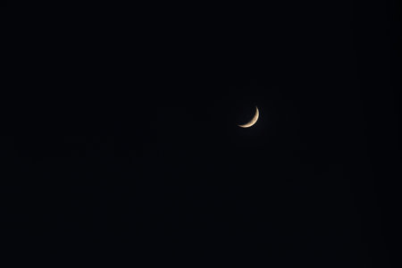 A crescent moon at night sky, dark minimal scene with soft glow and calm mood
