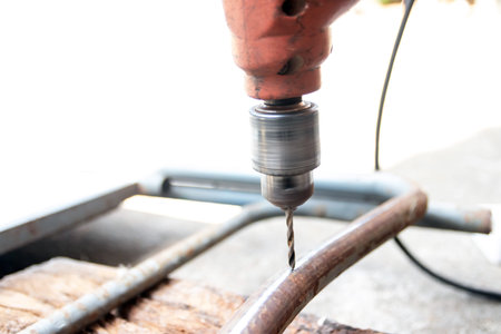 A handheld drill creating hole in metal frame with sparks and focused motion, energetic diy workshop...