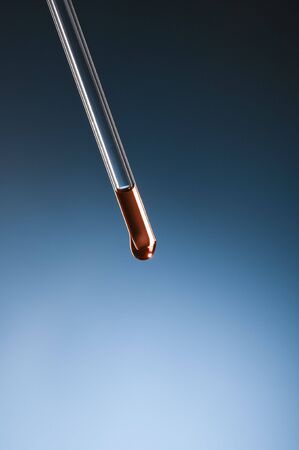 dropper with red liquid on blue gradientの写真素材