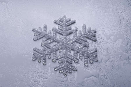 single snowflake with drops on light blue background 