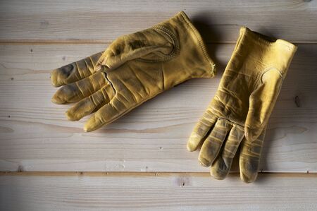 used yellow leather gloves on wood groundの写真素材