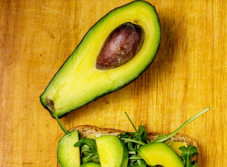 Avocado toast with rucolla on wooden table.