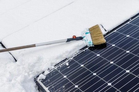 Photovoltaic panels on the roof cover with snow, with a bass-broom in the winter.の写真素材