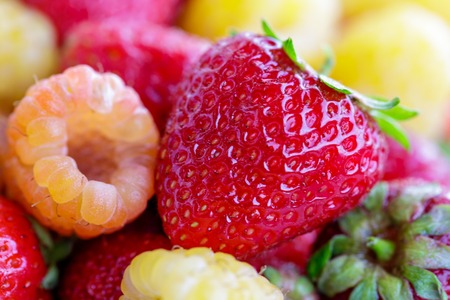 bio yellow raspberries with red strawberries. close up.の写真素材