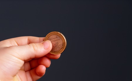 Child holding euro coin in his hand. Pocket money stock image. Poor low income group. Dark background. - Image. Close upの写真素材