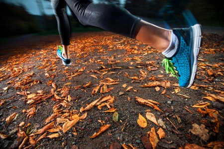 young woman running in the early evening autumn leavesの写真素材