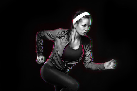 Beautiful young jogging woman. Isolated over black background (colored, retouched)の写真素材