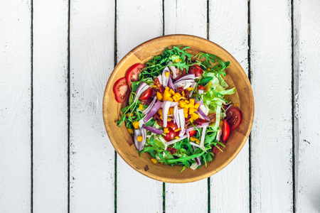fresh colorful vegetable salad on a white wooden tableの写真素材