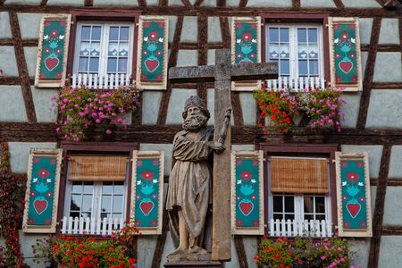 Stone cross in front of an old half-timbered house of Kaisersbergの写真素材