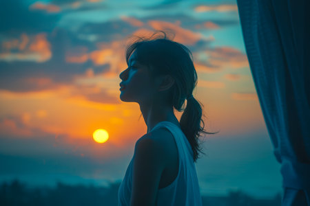 Serene Young Woman Enjoying a Breathtaking Sunset from a Tropical Balcony, Reflective Quiet Moment in Nature AI Generativeの素材