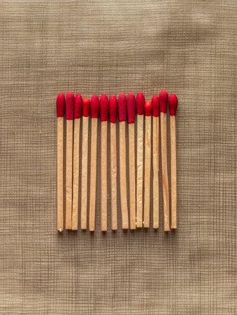 Symmetrical Arrangement of Wooden Matches with Red Tips on Textured Beige Surface Artistic and Minimalist Photography AI Generativeの素材