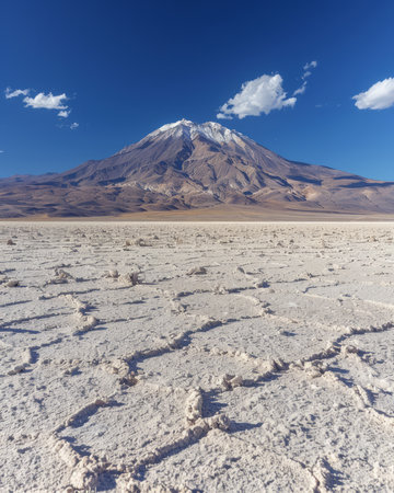 Awe-inspiring panorama showcasing a majestic snow-capped mountain towering over a parched and fragmented terrain The azure sky above contrasts the icy summit, highlighting the mesmerizing beauty of Earth&#39;s geological wonders A breathtaking winter landscape that evokes tranquility and inspires awe at nature&#39;s grandeur AI Generativeの素材