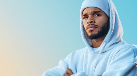A powerful portrait of a confident Black man in a stylish hoodie, standing against a minimalist background His calm expression and determined stance exude strength and self-assurance The image captures a focused gaze, a bold look, and an unwavering determination, reflecting inner strength, ambition, and a clear vision for success AI Generativeの素材
