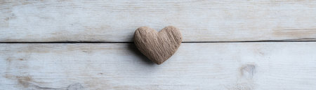 A textured, heart-shaped object sits centered on light wood, a minimalist symbol of love It's not romantically embellished, but rather conveys simple care This design, with its understated affection and wooden background, is ideal for clean graphics or Valentine's content, emphasizing simplicity AI Generativeの素材