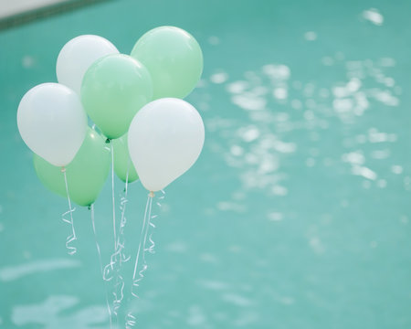 Floating green helium balloons grace a serene outdoor gathering, drifting above a tranquil pool This joyful image embodies happiness and festivity, perfect for invitations or adding a touch of whimsy The calming, lighthearted scene conveys a celebratory atmosphere with a festive and graceful feel AI Generativeの素材