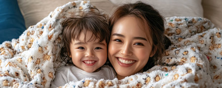This image radiates warmth, depicting an Asian mom and child snuggled under a blanket during a cozy movie night It captures the joy of family bonding, love, and happiness within their living space A perfect scene of precious memories being created in a beautiful family setting AI Generativeの素材