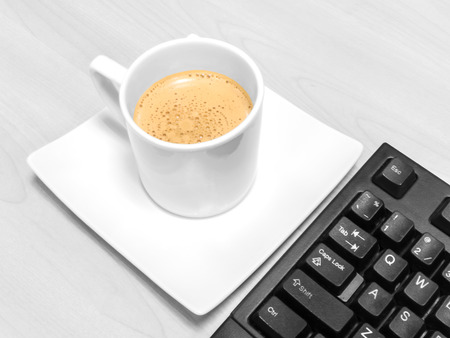 Cup of coffee with keyboard in black and white backgroundの写真素材