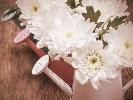 White bouquet flowers in watering can withvintage filter effectの写真素材