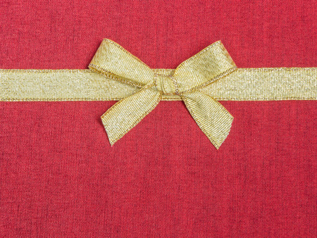 Golden ribbon and bow on red silk fabricの写真素材